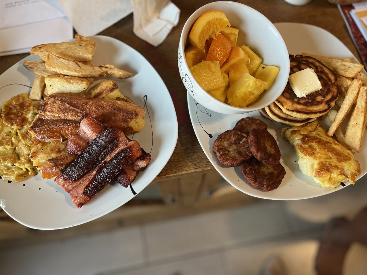 Breakfast plates with eggs, bacon, pancakes and fruit