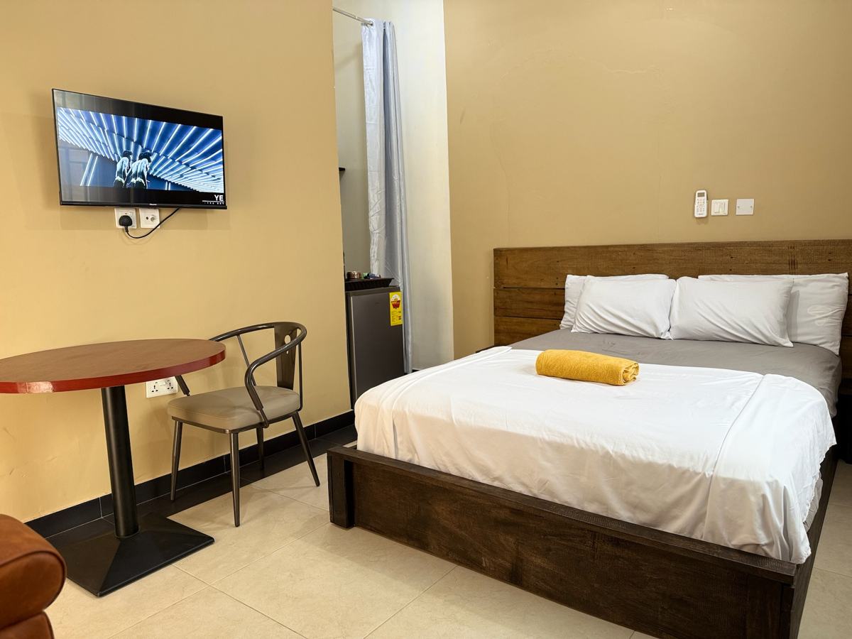 Queen studio suite with bed, wall-mounted TV and table