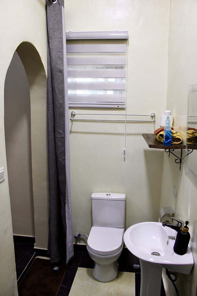 Queen studio suite bathroom with toilet, sink and shower curtain